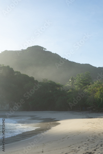 Картината върху платно A serene beach with gentle waves and lush green hills in the background