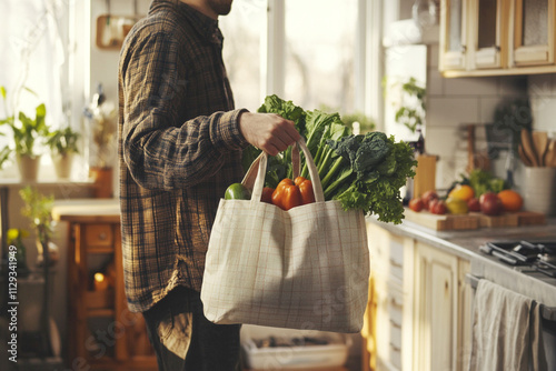 Man holding reusable bag with fresh vegetables in a cozy kitchen with natural light photo