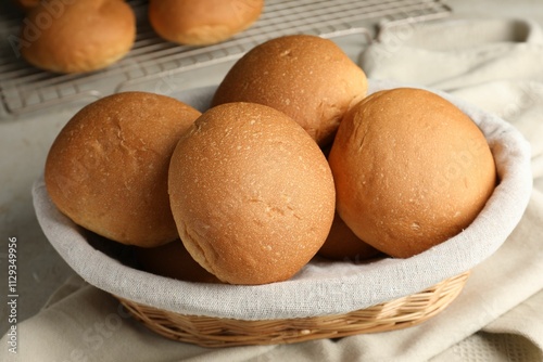 Fresh tasty buns in basket on table, closeup