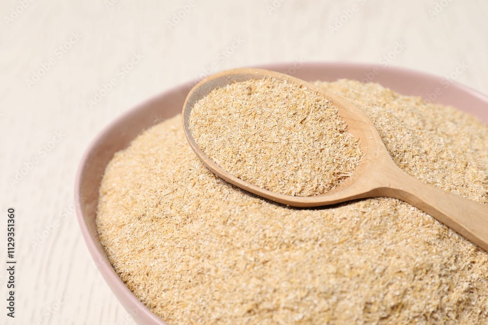 Oat bran in bowl and spoon on light table, closeup Oat bran in bowl and spoon on light table, closeup