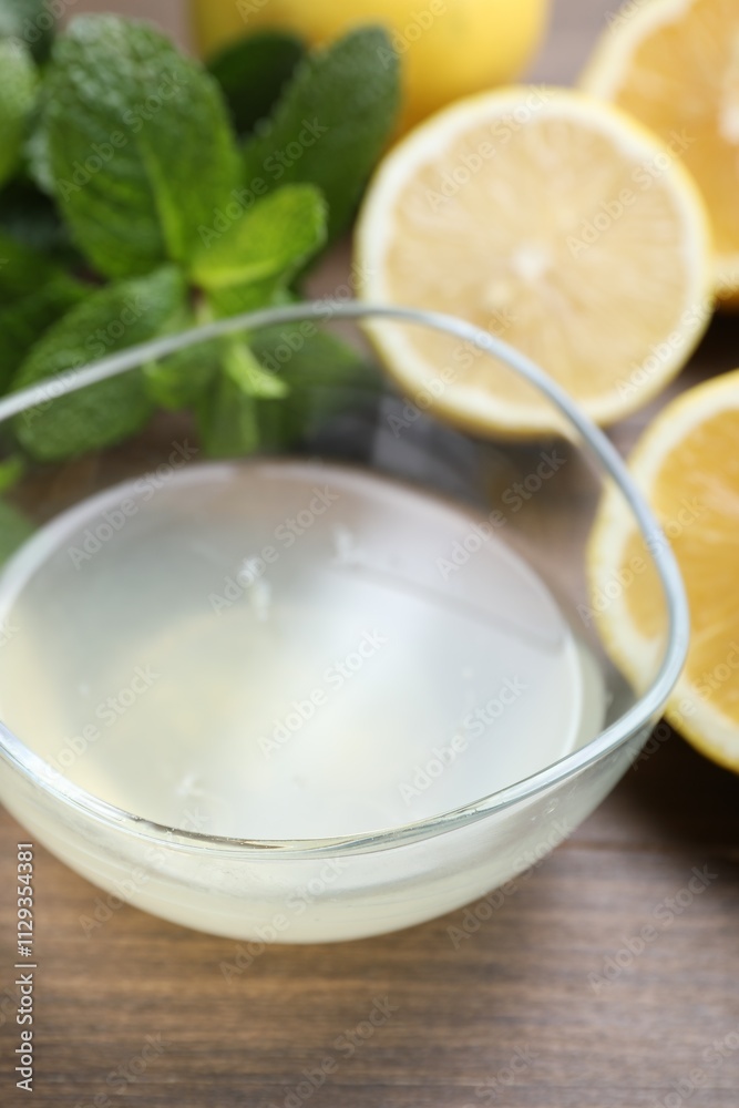 Fresh lemon juice in bowl, fruits and mint on wooden table, closeup Fresh lemon juice in bowl, fruits and mint on wooden table, closeup