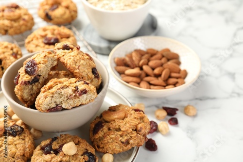 Delicious oatmeal cookies with raisins and nuts on white marble table, closeup