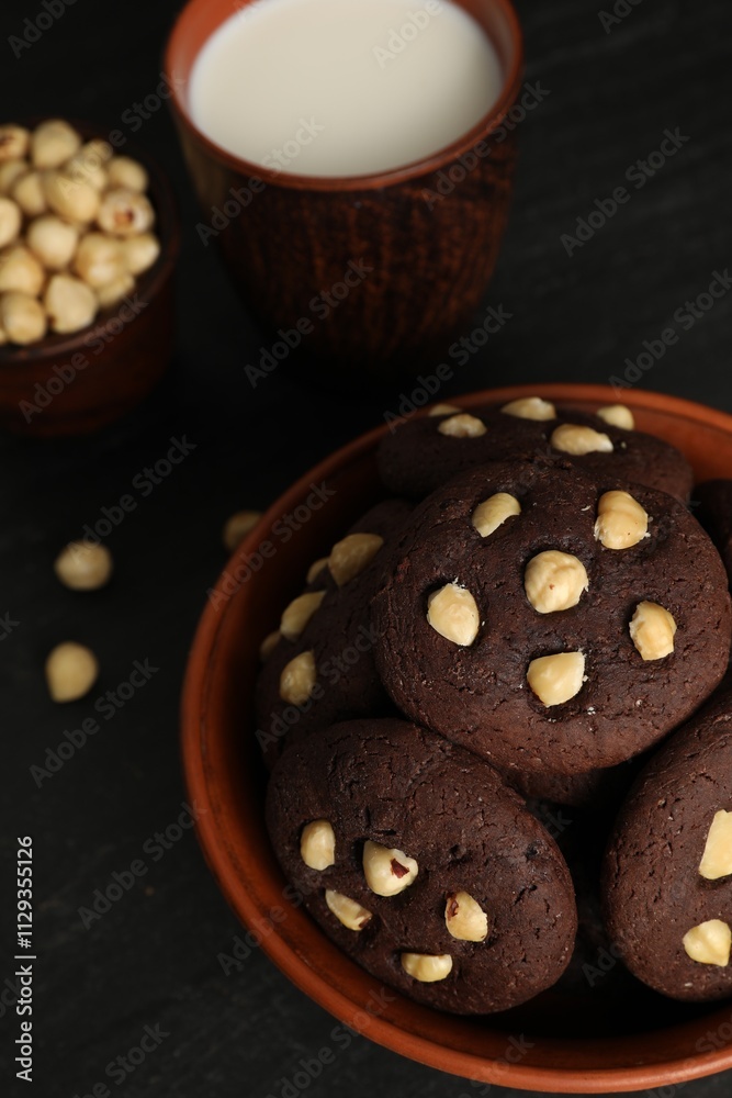 Tasty chocolate cookies with hazelnuts and milk on black table, closeup Tasty chocolate cookies with hazelnuts and milk on black table, closeup