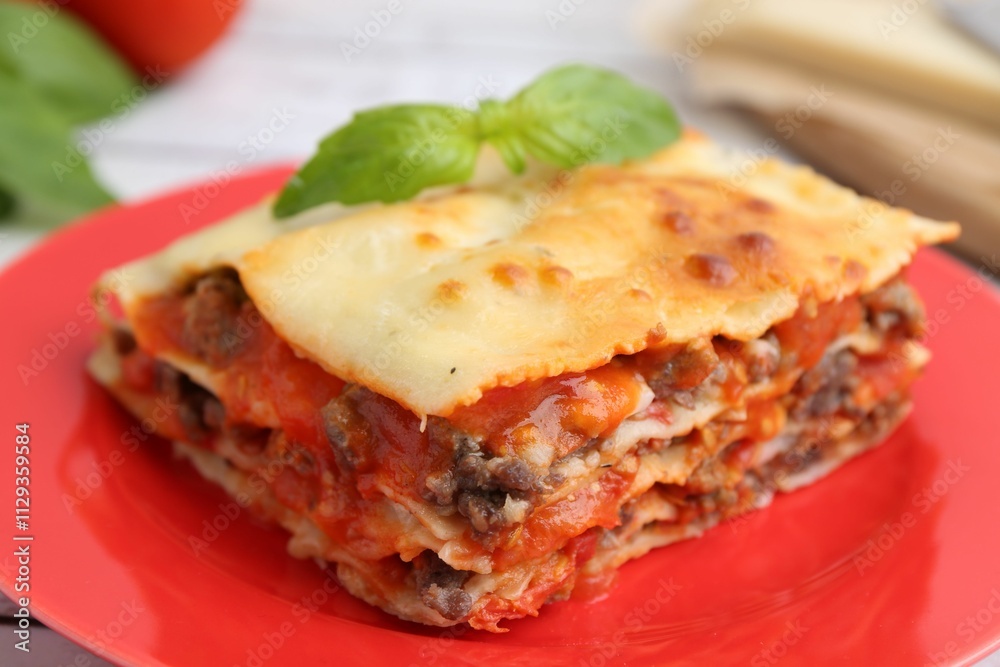 Piece of delicious cooked lasagna with basil on table, closeup