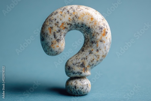 A single stone question mark placed on a blue surface, suitable for use in educational or decorative contexts photo