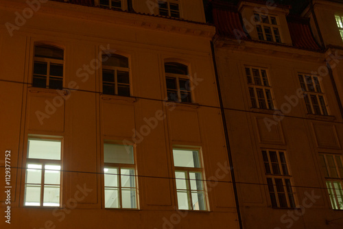 An impressive building adorned with numerous windows is beautifully illuminated during the nighttime hours, creating a captivating scene