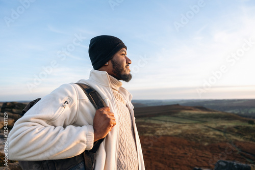 Photography Man in winter attire enjoys a scenic view during sunset from a hilltop in a tran