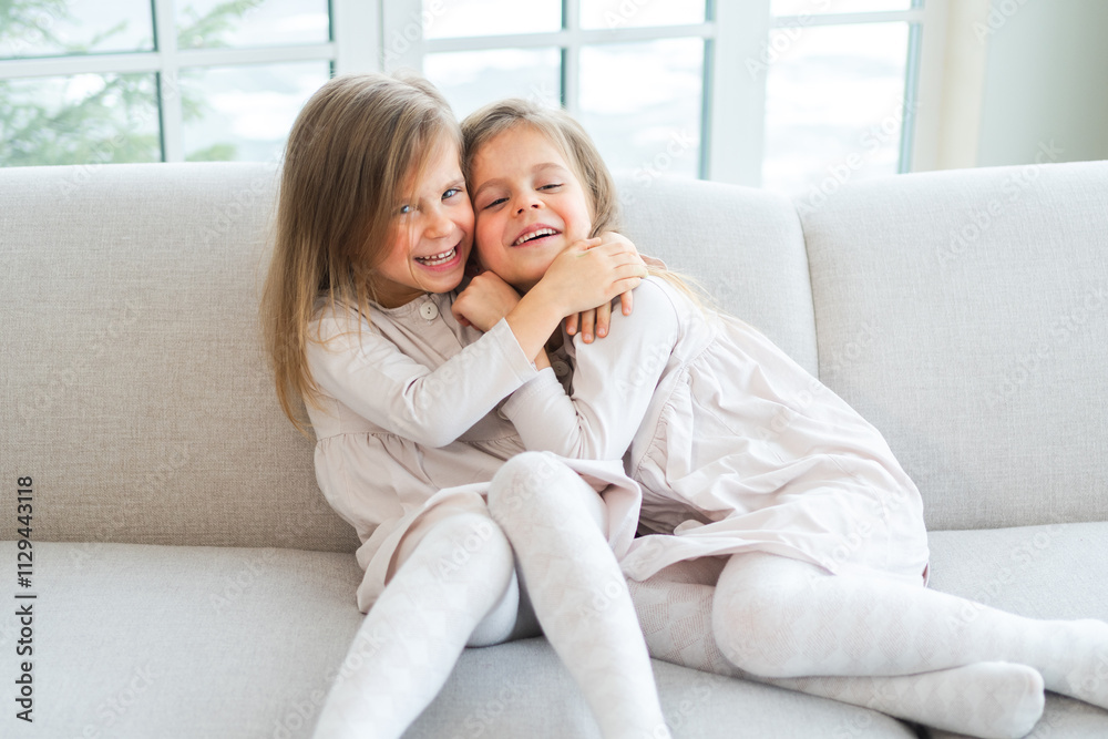 Happy family sisterly love. Two funny little twin sisters girls hugging with love care playing together at home indoors. Happy children lifestyle. Identical twin girls hugs. Girls friendship and youth Happy family sisterly love. Two funny little twin sisters girls hugging with love care playing together at home indoors. Happy children lifestyle. Identical twin girls hugs. Girls friendship and youth