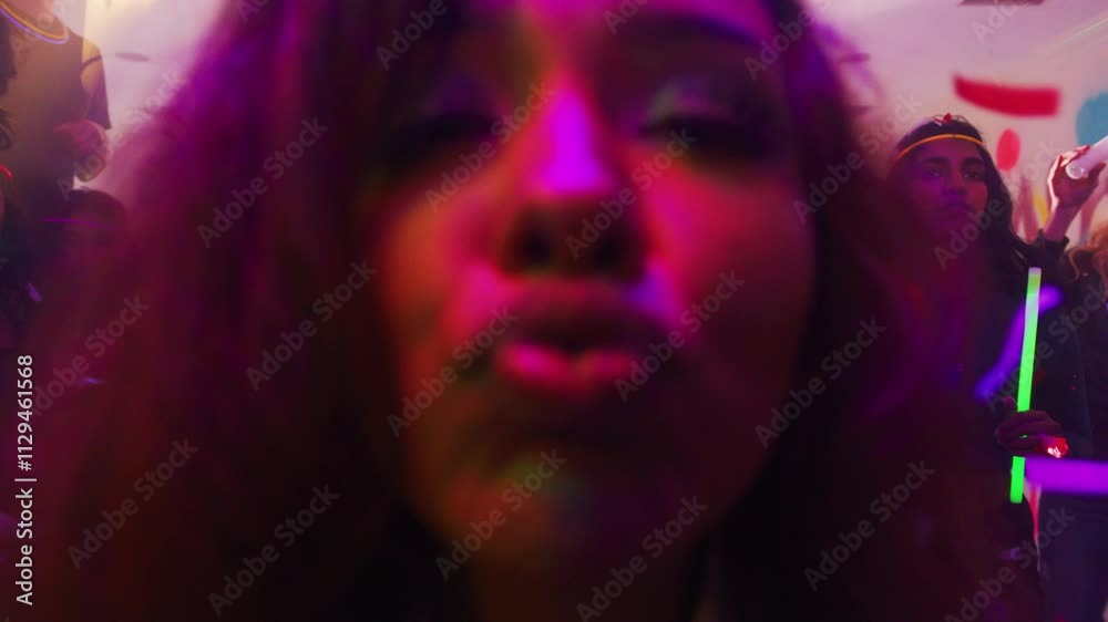 Shot where an attractive woman in a house party looks at the camera and kisses the lens.