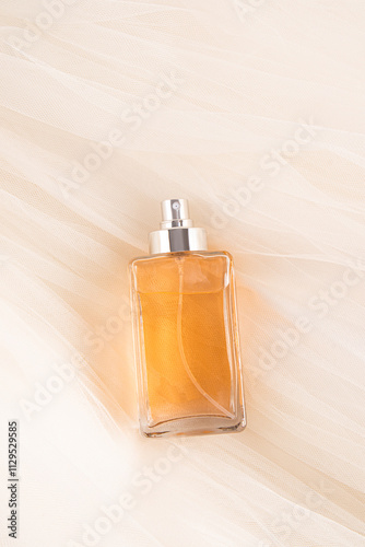 Elegant square perfume bottle with amber liquid on fabric background