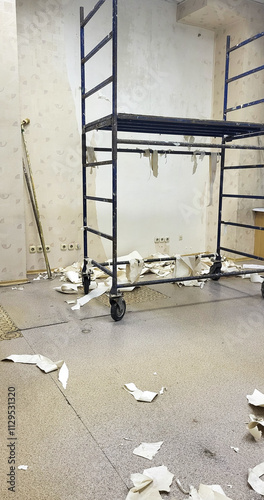 Removing old wallpaper. Repair. A ladder is leaning against a wall with a pile of paper on the floor