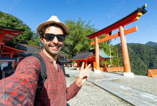 Handsome young tourist enjoying summer holiday in  Japan - Traveling life style concept with smiling man taking selfie on city street - Tourism and summertime vacation concept photo