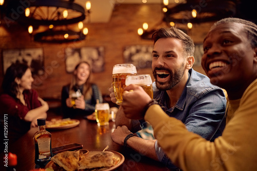 Happy male friends having fun and toasting while drinking beer in pub. photo