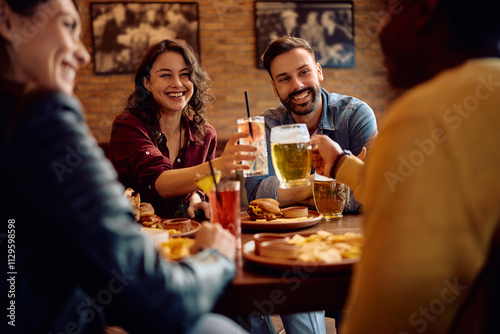 Multiracial group of friends toasting while eating in bar.