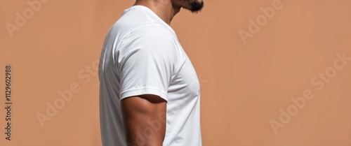 man in blank white t-shirt posing sideways against warm orange background
