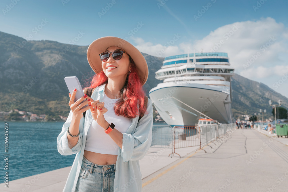 Young woman using smartphone while enjoying vacation near cruise ship in Kotor, Montenegro