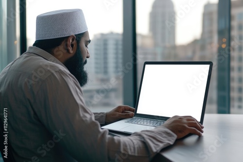 Middle Eastern man using laptop with blank screen.