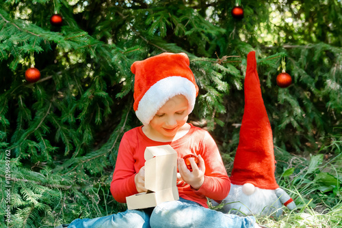 Child kid waiting for Christmas.little boy opening gift box near fir tree.winter festive holidays,family.Merry Christmas eve,New Year,Happy Holidays photo