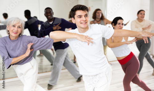 Smiling dark-haired young guy attending group choreography class, learning modern dynamic dances. Concept of active lifestyle ..