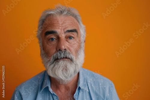 Elderly man in blue shirt poses for camera in studio