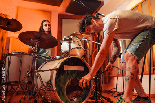 Sound technician is adjusting microphone for drums recording at studio