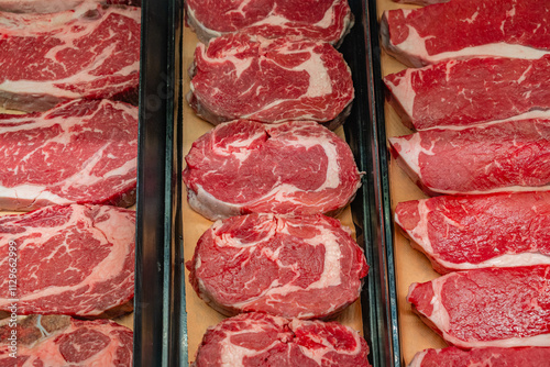 Various cuts of meat on display in grocery store refrigerator case.