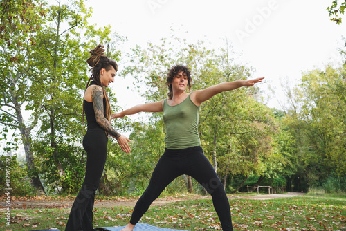 Transgender couple practicing yoga together in a park photo