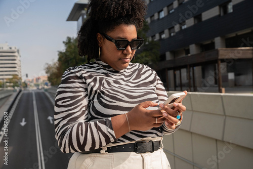 Young woman in zebra print top using smartphone in urban setting photo