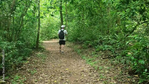 Young man exploring a trail in the middle of the forest. Photographer taking photos of nature in the forest. Happy photographer letting himself be surprised by the beauty that surrounds him