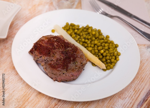 Fried beef cutlet with green peas on a plate photo