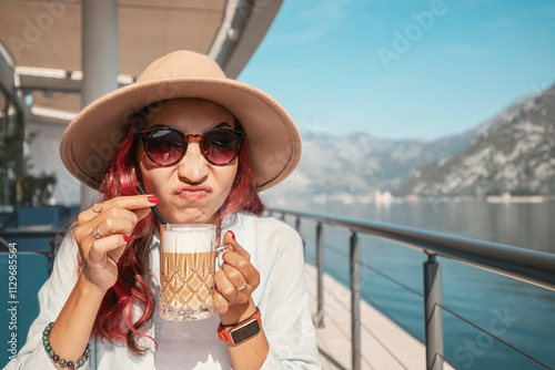 Tourist making a disgusted face while drinking a bad coffee in an outdoor cafe by the sea photo