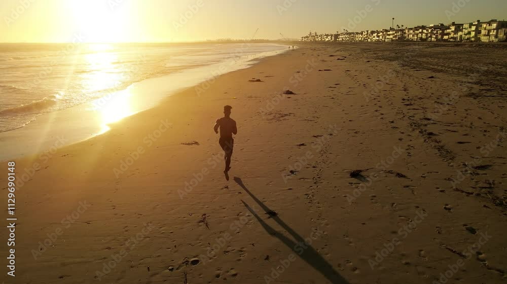 Aerial shot of a Athletic African American Man jogging on the beach at sunset