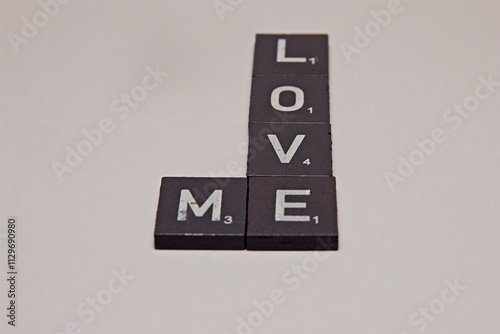 Gray Scrabble Letters making the word Love Me, on a White background photo