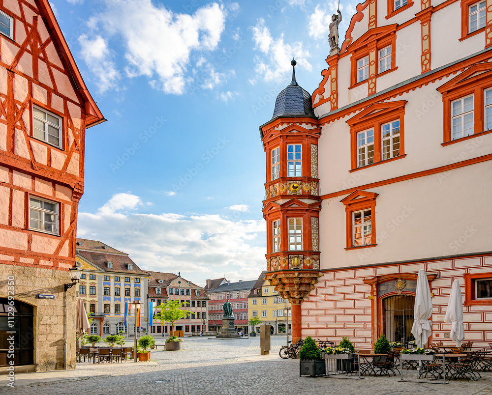 Obraz premium Blick zum Marktplatz und dem farbenfrohen Coburger Stadthaus mit zweistöckigem Erker und historischen Altstadthäusern von der Herrngasse aus gesehen, Coburg, Bayern, Deutschland
