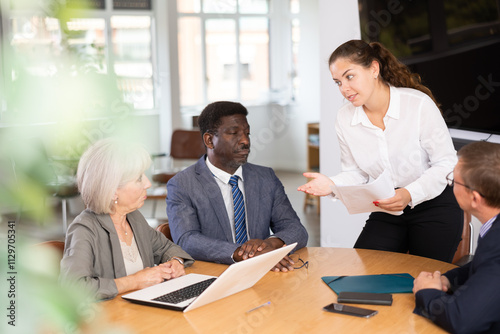 Business men and woman engaged in conversation sitting around table in conference room