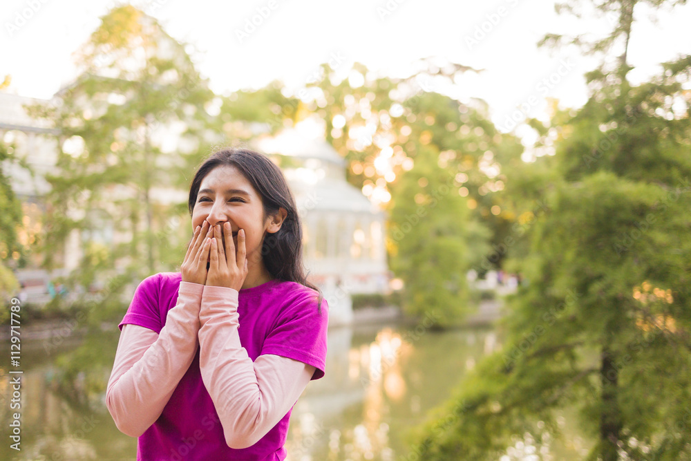 Peruvian student enjoying a day at el retiro park in madrid, covering her mouth while laughing Peruvian student enjoying a day at el retiro park in madrid, covering her mouth while laughing