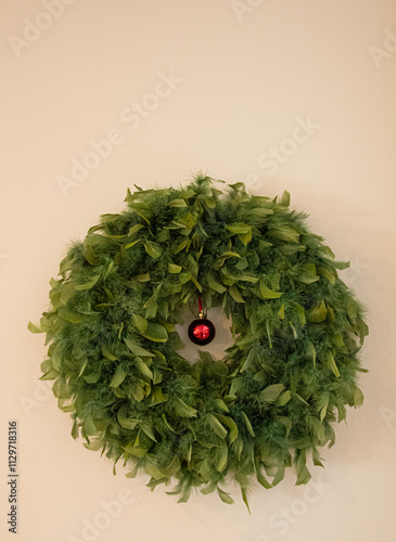 A green Christmas wreath on a wall with room for copy at the top