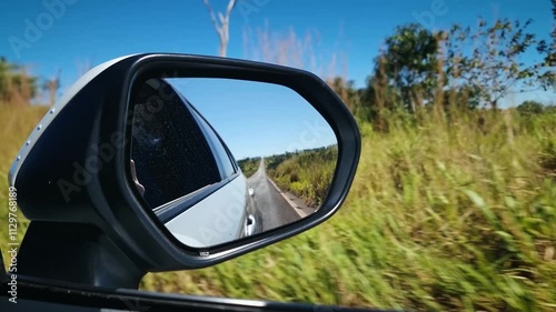 Car trip on the road seen through the reflection of the car's rear view mirror.
