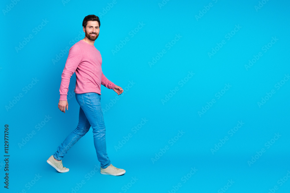 Confident man walking casually in stylish outfit against a vibrant blue background Confident man walking casually in stylish outfit against a vibrant blue background