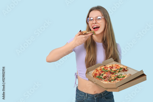 Teenage girl eating delicious pizza Margherita on blue background