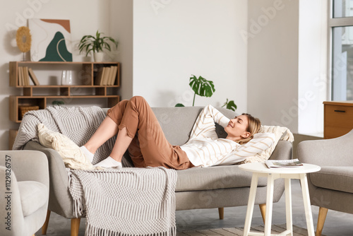 Cuadro en lienzo Young woman resting on grey sofa at home