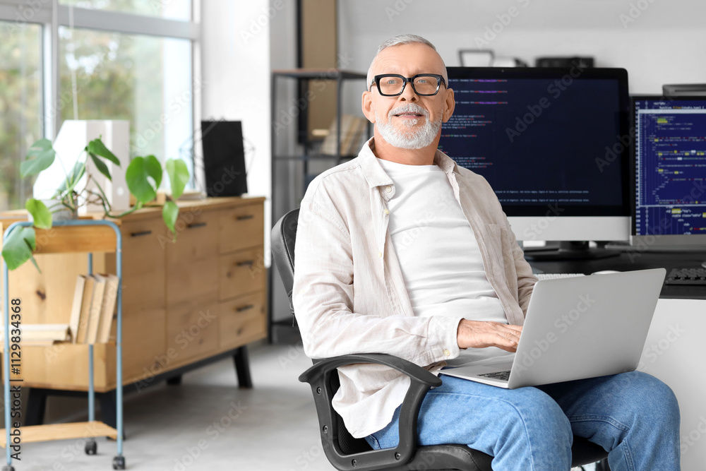 Mature programmer working with laptop in office Mature programmer working with laptop in office