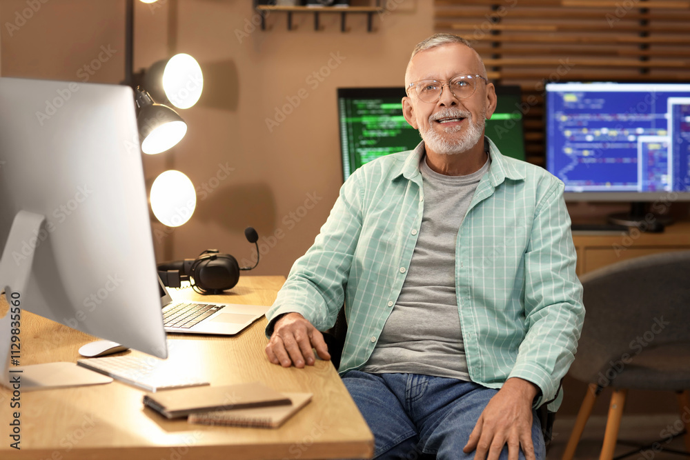 Mature programmer sitting at office in evening Mature programmer sitting at office in evening