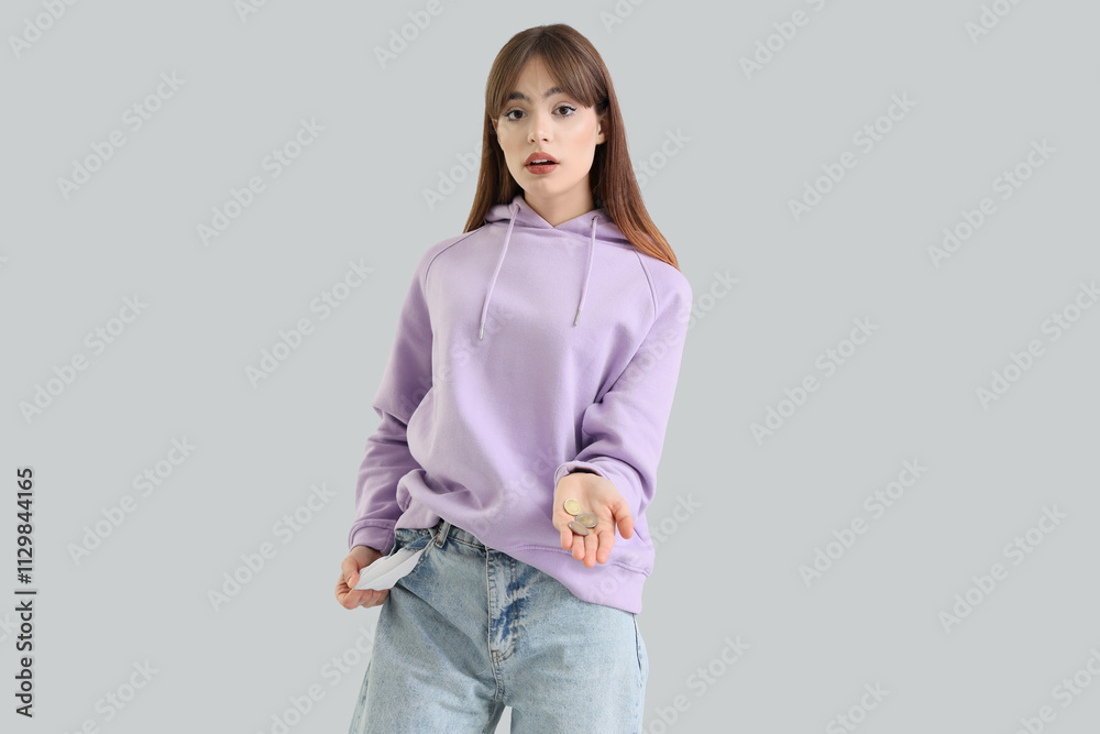 Upset young woman with empty pocket and coins on light background Upset young woman with empty pocket and coins on light background