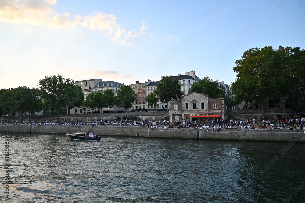 Fototapeta premium Gente al atardecer a orilla del Río Sena, en París Francia