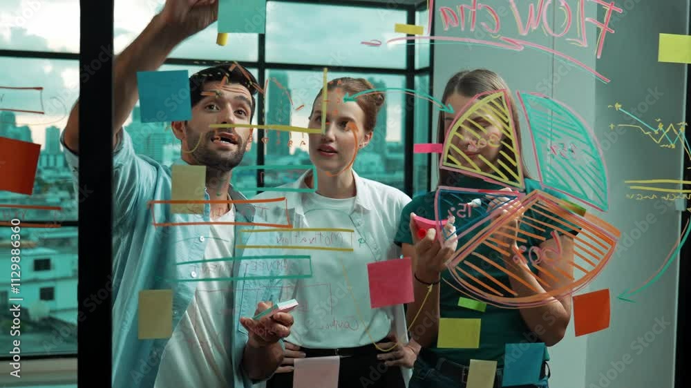 Group of professional business team working together, discussing and writing at sticky notes about marketing idea,plan, strategy at glass wall with graph and colorful sticky notes. Tracery