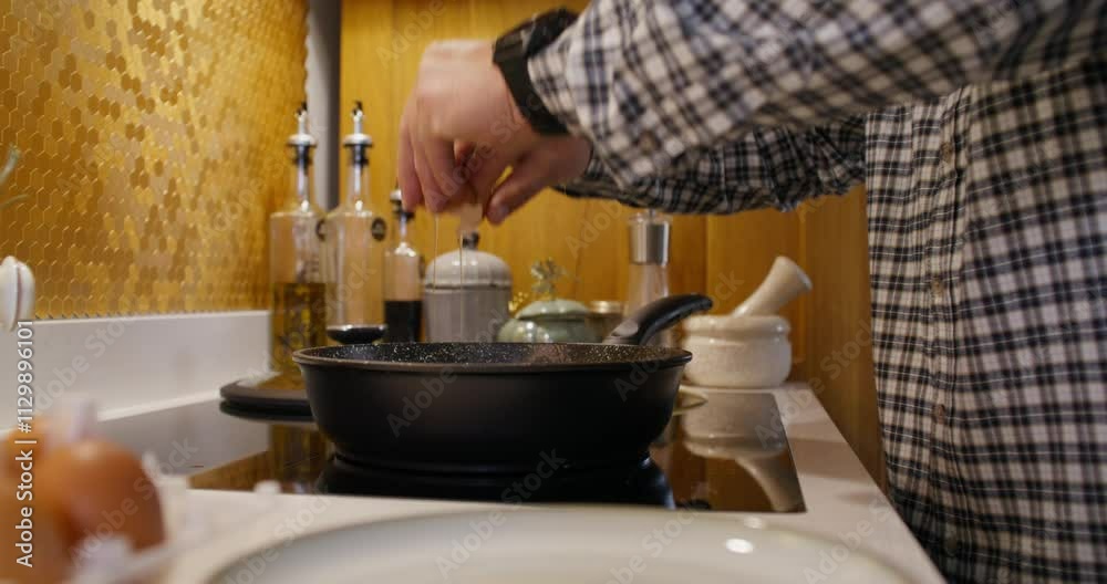 A man breaks eggs into a frying pan. Cooking breakfast at home. Close-up of his hand, an unrecognizable person A man breaks eggs into a frying pan. Cooking breakfast at home. Close-up of his hand, an unrecognizable person