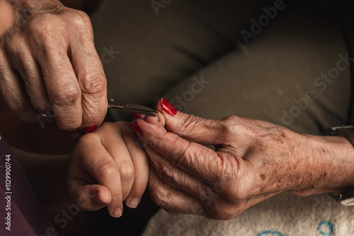 A granddaughter and her grandmother cutting her fingernails