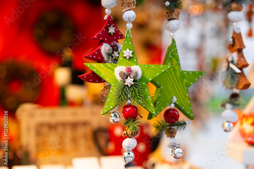 Colorful wooden star ornaments in green and red, adorned with pinecones, small bells and festive decorations, hanging in vibrant, holiday-themed display