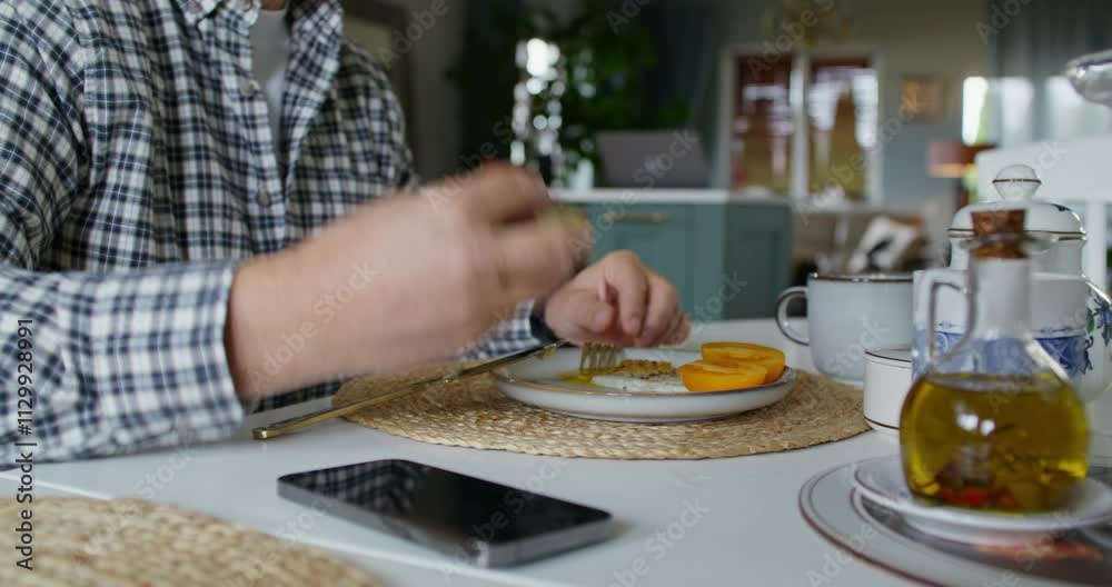 A man eats his breakfast sitting at the kitchen table at home. Daylight, proper nutrition A man eats his breakfast sitting at the kitchen table at home. Daylight, proper nutrition
